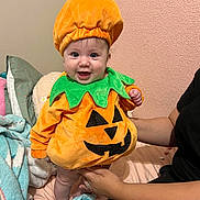 Aylani is registered to the contest to win money with this photo: baby, bed, blanket, celebration, child, costume, cozy, cute, festive, green, halloween, happy, holding, indoor, infant, orange, person, pillow, pumpkin_costume, smile
