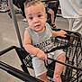 baby, shopping_cart, child, store, aisle, person, clothing, footwear, floor, hand, face, expression, shopping, retail, casual_wear, seat, black, gray, indoor, people