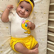 Alba a rejoint le concours — aidez-le/la à gagner de superbes lots ! baby, infant, smiling, yellow_headband, yellow_shorts, tweety_bird, white_shirt, lying_down, mattress, patterned_bedding, cute, happy, child, flexing_arm, indoors, portrait, skin, baby_clothes, headwear, playful