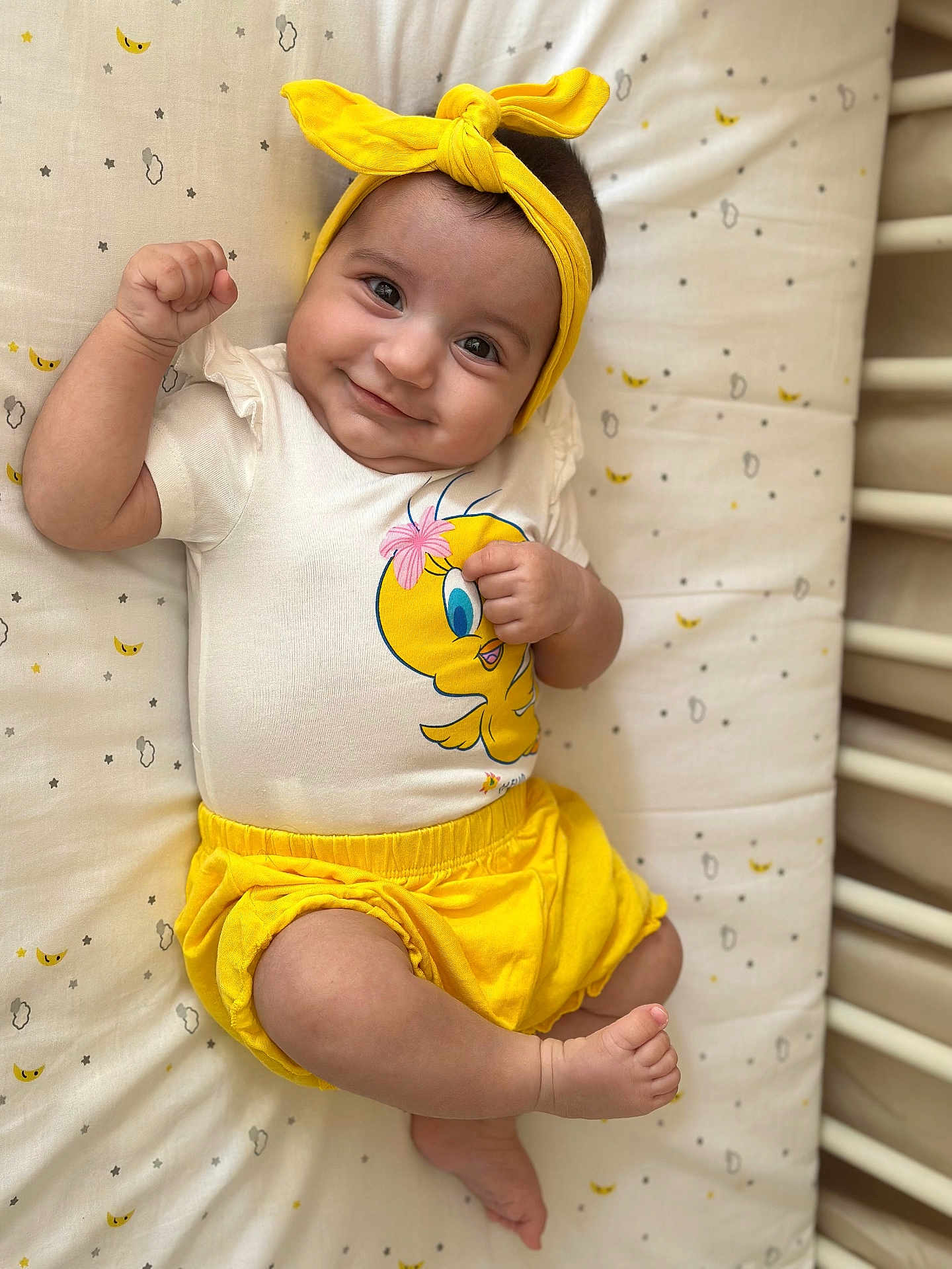 Alba a rejoint le concours — aidez-le/la à gagner de superbes lots ! baby, infant, smiling, yellow_headband, yellow_shorts, tweety_bird, white_shirt, lying_down, mattress, patterned_bedding, cute, happy, child, flexing_arm, indoors, portrait, skin, baby_clothes, headwear, playful