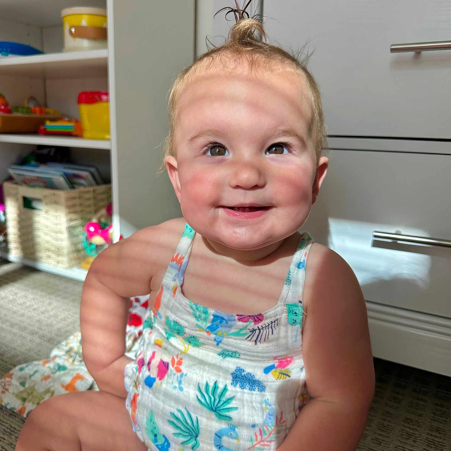 Scarlett is registered to the contest to win money with this photo: baby, basket, cabinet, carpet, child, cute, expression, face, hair, happy, indoors, person, playroom, romper, shadow, sitting, skin, smiling, sunlight, toy