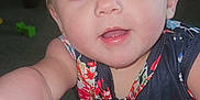 Lillian joined the competition — help win amazing prizes! toddler, child, blue_eyes, floral_clothing, smiling, indoor, curious, baby, face, hand, couch, carpet, furniture, portrait, young_child, skin, person, cute, expression, home