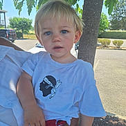 Alessio a rejoint le concours — aidez-le/la à gagner de superbes lots ! toddler, child, outdoor, tree, shirt, white_clothing, blue_eyes, blonde_hair, person, holding, daylight, parking_lot, nature, casual, portrait, curious, expression, summer, sunlight, candid