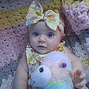 Neveah joined the competition — help win amazing prizes! baby, infant, bow, headband, plush_toy, stuffed_animal, blanket, crocheted_blanket, portrait, blue_eyes, gaze, hand, dress, pattern, pastel_colors, nursery, lying_down, cute, soft_texture, accessories