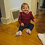 toddler, child, smiling, indoor, wooden_floor, maroon_top, navy_pants, socks, white_wall, vent, blanket, polka_dots, happy, baby, flooring, person, cute, seated, home, cozy