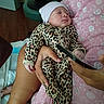 newborn, baby, sleeping, infant, portrait, leopard_print, onesie, beanie, hat, blanket, pink, adult_hand, indoor, nursery, cozy, sitting, cradle, phone, close_up, peaceful