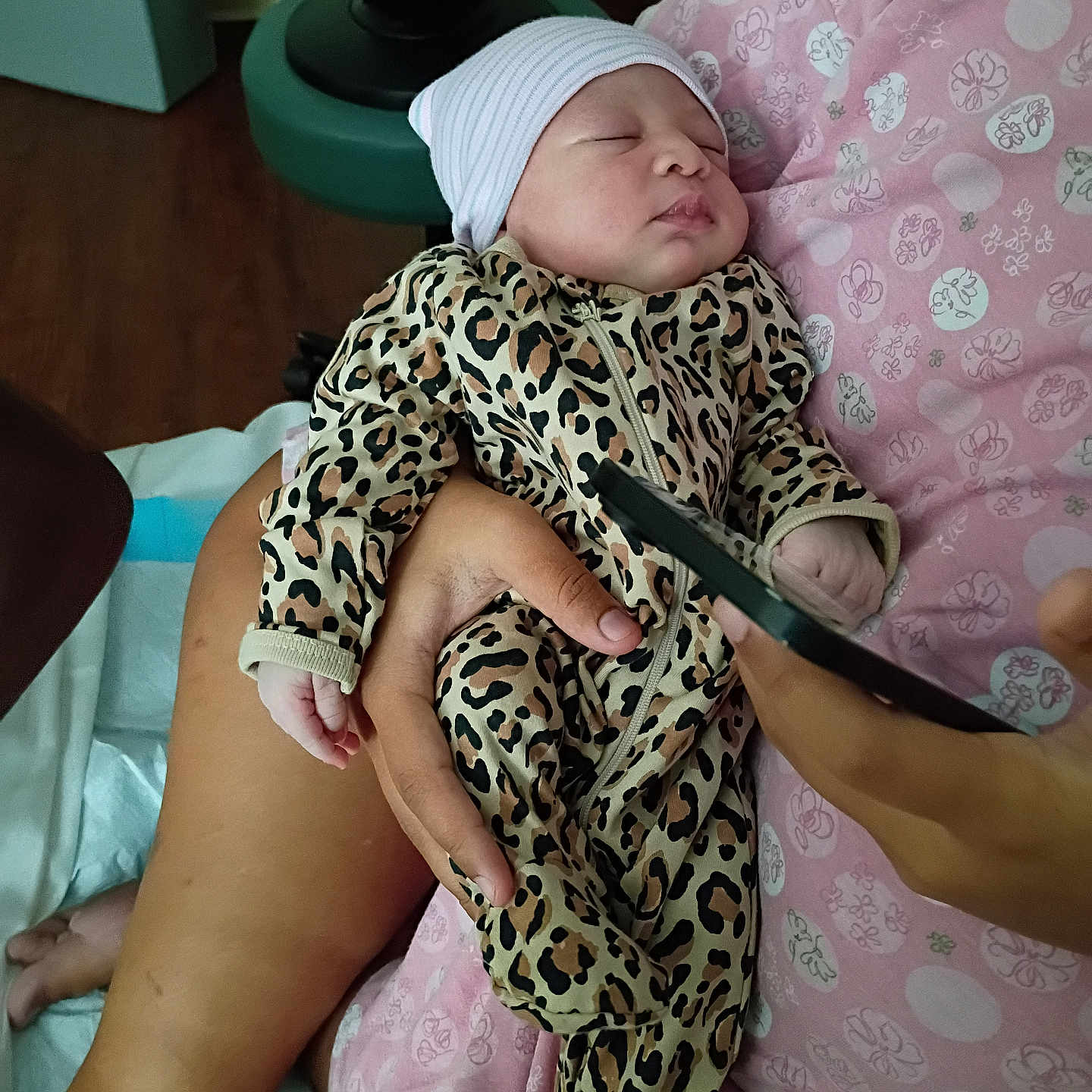 Leilani joined the competition — help win amazing prizes! newborn, baby, sleeping, infant, portrait, leopard_print, onesie, beanie, hat, blanket, pink, adult_hand, indoor, nursery, cozy, sitting, cradle, phone, close_up, peaceful
