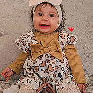 Carla is registered to the contest to win money with this photo: baby, child, smiling, headband, bow, dress, hearts, toy, teether, couch, knitted_tights, happy, cute, indoors, portrait, infant, sitting, clothing, warm_colors, head