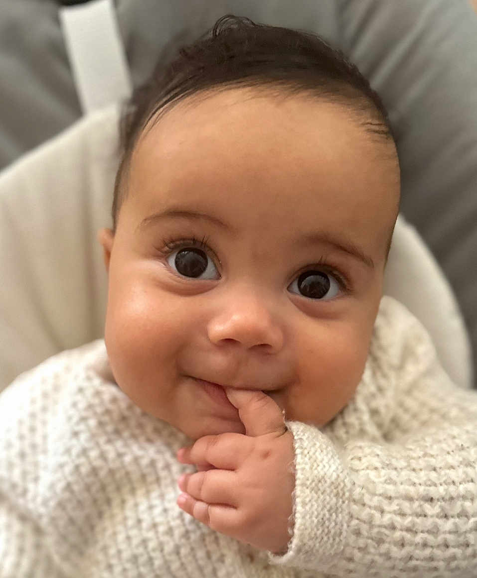 Devonte is registered to the contest to win money with this photo: baby, infant, face, hand, knitted_sweater, cute, eyes, fingers, close_up, smile, child, person, skin, portrait, soft_light, indoors, cozy, young, expression, warm