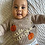 baby, infant, smiling, sweater, knitted, pumpkin, cute, lying_down, white_blanket, closeup, child, portrait, happy, face, eyes, mouth, button, clothing, soft_texture, adorable