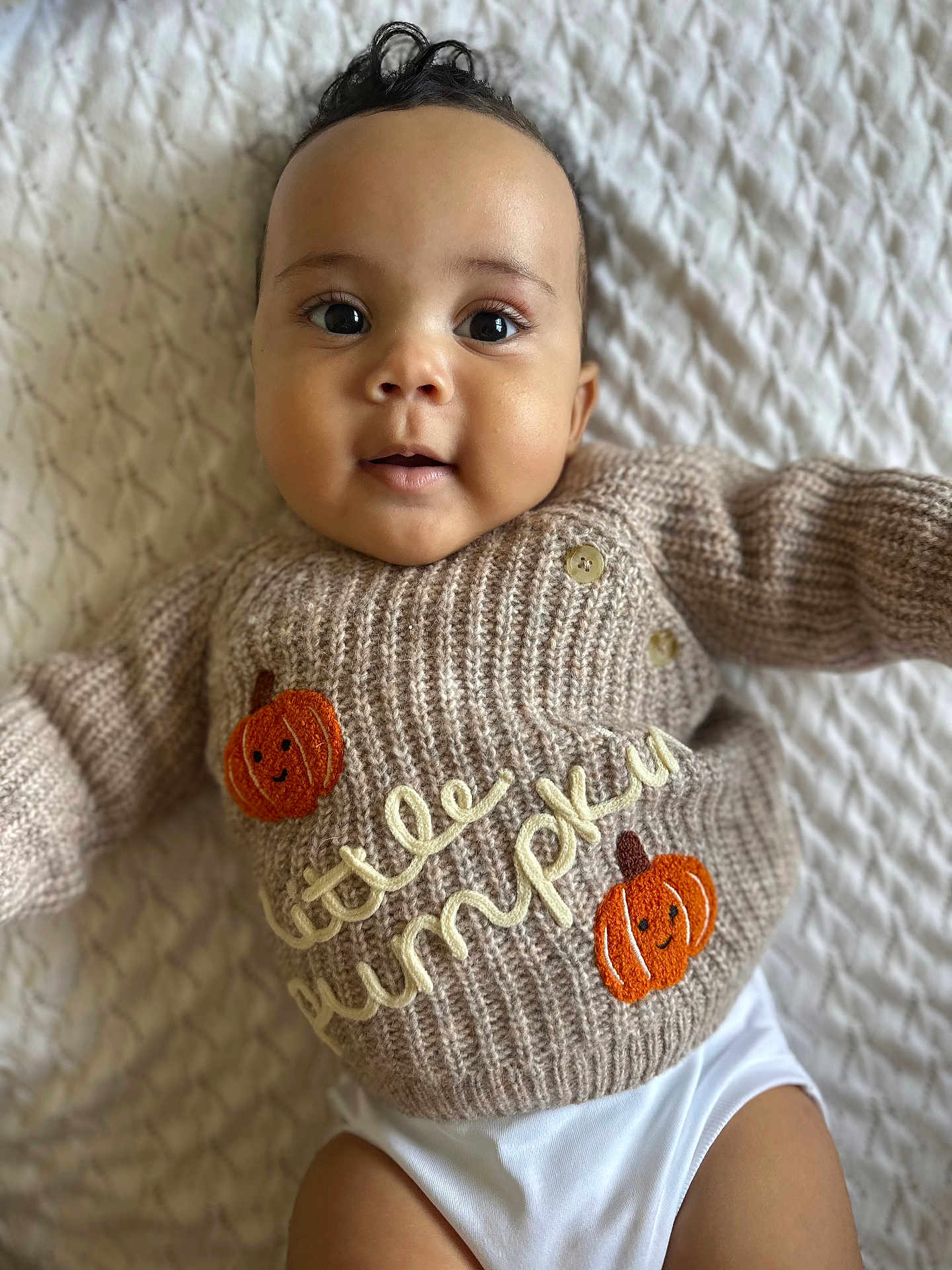 Devonte joined the competition — help win amazing prizes! baby, infant, smiling, sweater, knitted, pumpkin, cute, lying_down, white_blanket, closeup, child, portrait, happy, face, eyes, mouth, button, clothing, soft_texture, adorable