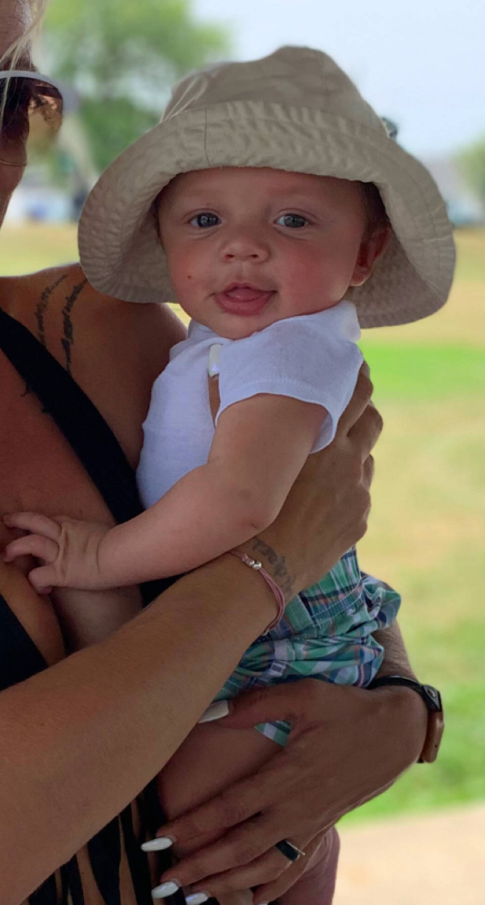 Makai is registered to the contest to win money with this photo: baby, baby_toddler_clothing, blond, cap, child, face, finger, fun, grass, hand, happy, hat, headgear, headwear, person, photograph, sitting, skin, smile, summer