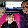 child, adult, car_seat, vehicle, glasses, smile, person, window, road, seatbelt, pink, hair, face, jacket, sunglasses, inside, travel, happy, family, portrait