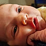 baby, close_up, face, hand, lying_down, infant, skin, eyes, mouth, expression, cute, newborn, soft_light, indoors, portrait, child, young, person, fingers, resting