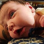 Storm is registered to the contest to win money with this photo: baby, infant, face, hand, tattoo, rope, yellow_clothing, skin, closeup, expression, indoors, person, portrait, curious, young_child, holding, wide_eyes, lying_down, background_blur, home