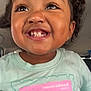 Zoey is registered to the contest to win money with this photo: toddler, child, smile, teeth, face, happy, eyelashes, earrings, curly_hair, tshirt, pastel_colors, closeup, portrait, joy, cute, indoor, person, young_child, expression, casual_clothing