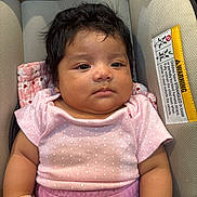 Luna is registered to the contest to win money with this photo: baby, infant, child, car_seat, clothing, pink_shirt, mittens, portrait, cute, face, young_child, indoor, seat, child_safety, fabric, soft_lighting, person, closeup, expressionless, polka_dot