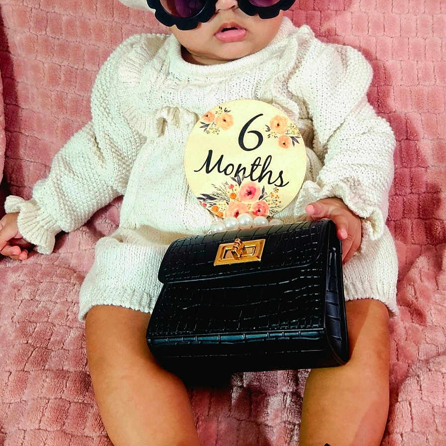 Naliya is registered to the contest to win money with this photo: accessories, baby, cap, clothing, face, footwear, glasses, hat, head, pants, person, photography, portrait, racket, shoe, sitting, sleeve, sport, sunglasses, wallet