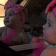Kimberlynn is registered to the contest to win money with this photo: baby, child, mirror, reflection, pink_bow, headband, indoor, dim_light, curious, face, clothing, person, young_child, portrait, infant, room, furniture, baby_girl, closeup, looking