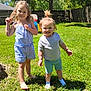 child, children, toddler, smiling, outdoor, grass, sunlight, summer, playful, curly_hair, romper, shorts, socks, backyard, tree, fence, happy, barefoot, greenery, daylight