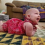 baby, infant, smiling, red_dress, quilt, carpet, living_room, couch, rocking_chair, blanket, child, happy, floor, home_interior, person, cute, playful, toddler, indoor, furniture