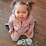 toddler, child, pink_hoodie, pigtails, smiling, indoor, wooden_floor, plush_toy, sitting, cute, young_child, face, person, toy, casual_clothing, happy, looking_up, kneeling, shoes, home
