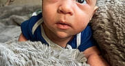 Isaiah is registered to the contest to win money with this photo: baby, infant, blanket, fur, couch, curious, face, head, indoors, person, portrait, skin, expression, blue_clothing, young_child, soft_texture, resting, cozy, closeup, newborn