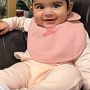 Kinza joined the competition — help win amazing prizes! baby, child, smiling, pink_headband, flower_accessory, bib, drool, pastel_clothing, sitting, chair, indoor, portrait, cute, happy, infant, black_leather, closeup, face, young_child, person