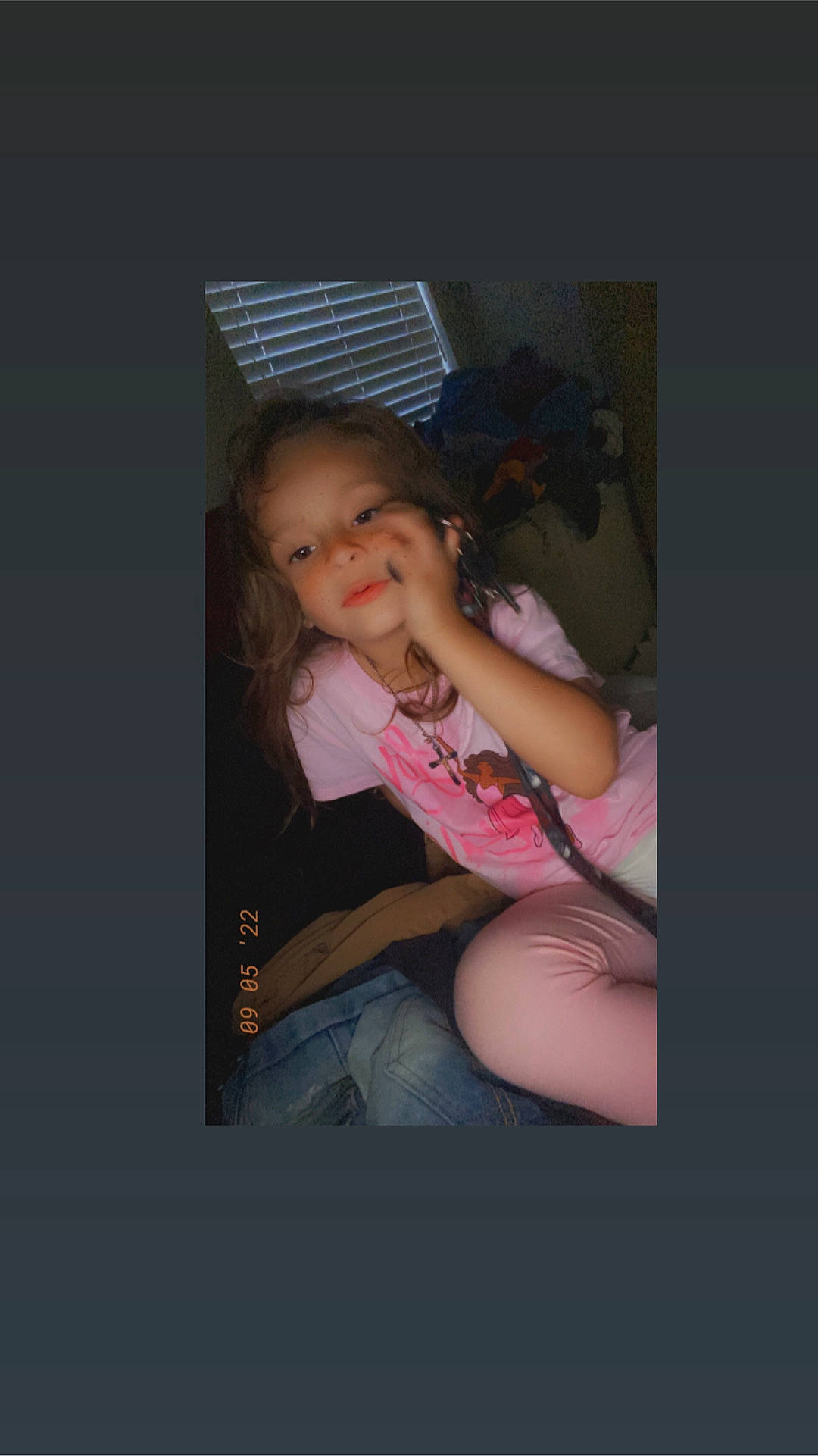 Athena is registered to the contest to win money with this photo: black_hair, darkness, elbow, eyelash, finger, flash_photography, fun, gesture, happy, human_leg, knee, lap, magenta, person, shorts, sitting, smile, t_shirt, thigh, toddler