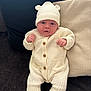 baby, infant, knit_hat, knit_suit, bear_ears, cozy, couch, pillow, hands, face, wide_eyes, sitting, clothing, indoor, cute, newborn, portrait, soft, warm, child