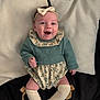 baby, smiling, headband, bow, pillow, knitted_sweater, floral, romper, socks, knee_high, lying_down, happy, cute, infant, child, indoors, fabric, soft, cozy, portrait