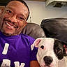 Wishbone is registered to the contest to win money with this photo: man, dog, smile, purple_shirt, couch, leather, indoor, pet, companion, happy, face, black_and_white_dog, casual, relaxing, friendship, portrait, seated, human, animal, cozy