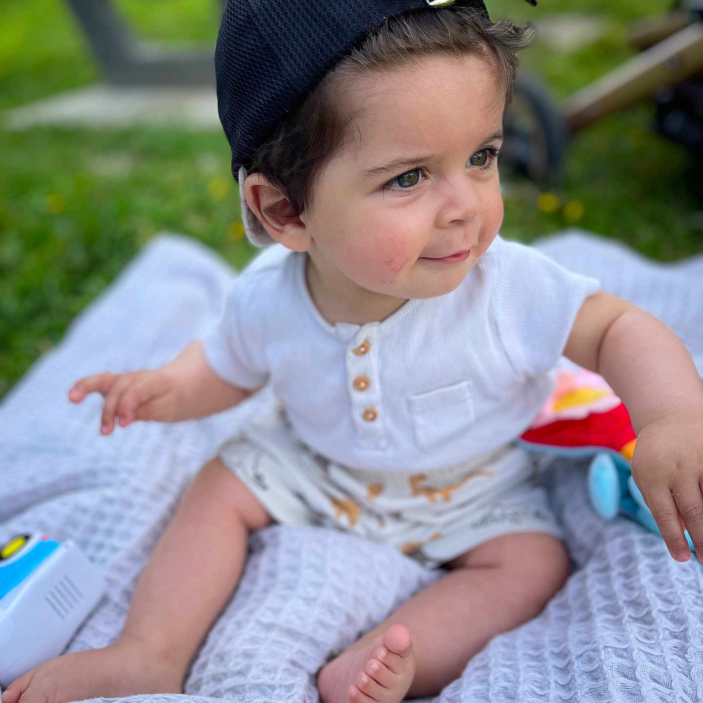 Nasser a rejoint le concours — aidez-le/la à gagner de superbes lots ! baby, barefoot, blanket, cap, child, cute, grass, happy, hat, outdoor, playtime, portrait, shorts, sitting, smiling, summer, toddler, toy, white_shirt, young_child