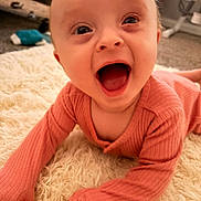 Alora is registered to the contest to win money with this photo: baby, infant, smiling, happy, mouth_open, pink_clothing, long_sleeves, lying_down, carpet, fluffy_rug, indoor, child, cute, portrait, person, young_child, head, face, expression, skin