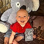 Maël participe au concours pour gagner de l'argent avec cette photo : baby, child, smiling, red_shirt, striped_shorts, plush_toy, koala, milestone_card, indoor, blanket, couch, happy, sitting, face, cute, infant, hands, feet, cozy, portrait