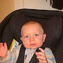 baby, child, car_seat, seat_belt, onesie, blue_eyes, toy, indoor, infant, safety, cute, small_hands, face, person, comfort, warm_clothing, young_child, expression, head, seat