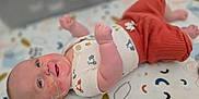 Weston is registered to the contest to win money with this photo: baby, infant, smile, lying_down, nasal_tube, medical_tape, cute_outfit, patterned_blanket, raised_fists, close_up, head, cheek, skin, person, child, indoors, colorful, soft_lighting, happy, small_arms