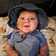 Weston joined the competition — help win amazing prizes! baby, infant, striped_shirt, hat, feeding_tube, medical_tape, smiling, happy, blue_eyes, blanket, animal_print, cute, child, person, indoors, portrait, closeup, chubby_arms, seated, soft_lighting