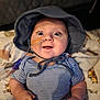 baby, infant, striped_shirt, hat, feeding_tube, medical_tape, smiling, happy, blue_eyes, blanket, animal_print, cute, child, person, indoors, portrait, closeup, chubby_arms, seated, soft_lighting