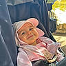 Inaya participe au concours pour gagner de l'argent avec cette photo : baby, child, stroller, hat, pink_clothing, smile, sunlight, outdoor, park, pond, greenery, pacifier, infant, happy, casual, seatbelt, cute, portrait, person, relaxed