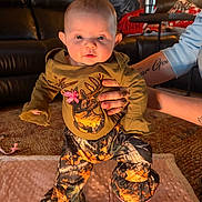 Arya joined the competition — help win amazing prizes! baby, camo_clothing, carpet, child, clothing, cute, eyes, face, indoors, infant, leather_couch, living_room, mouth, person, pink_bow, soft_blanket, standing, supporting_hands, tattooed_hands, warm_lighting