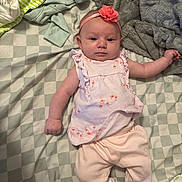 Gabriella is registered to the contest to win money with this photo: baby, infant, girl, clothing, headband, flower, blanket, bedspread, soft, pink, flamingo, sleepwear, lying_down, cute, child, indoors, fabric, comfort, person, newborn