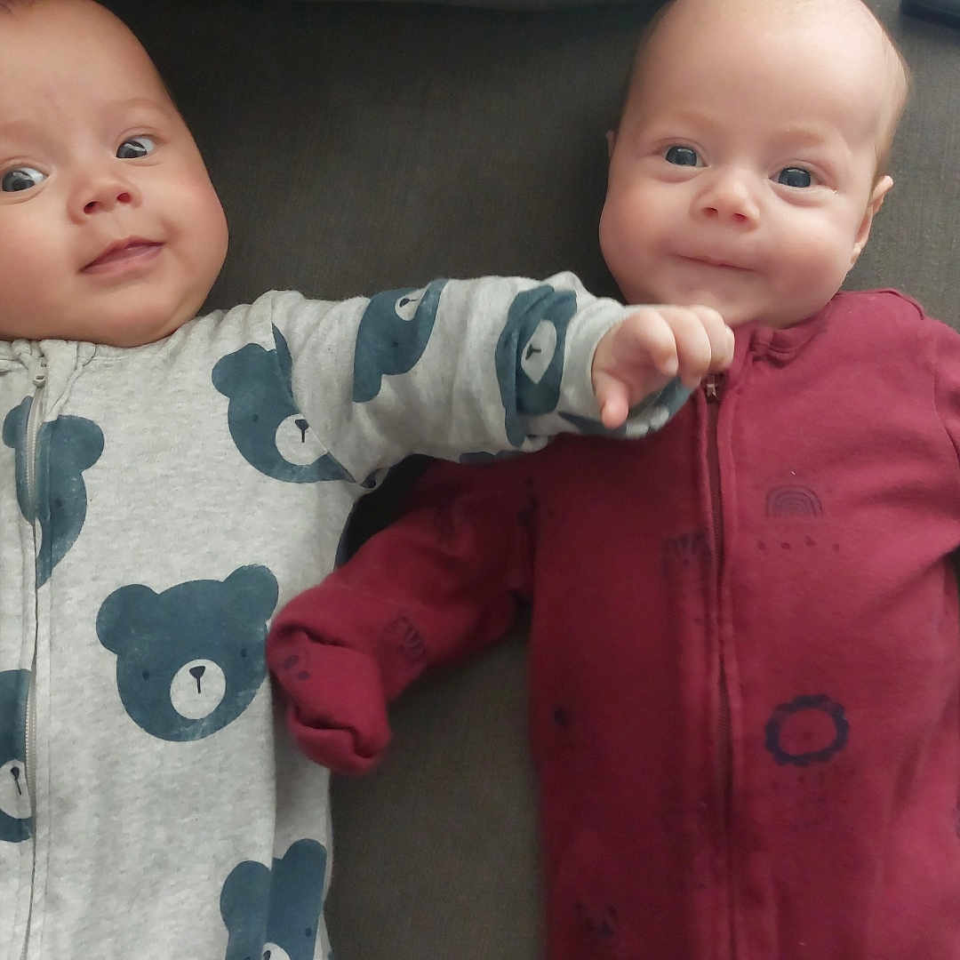 Ethan And Josh is registered to the contest to win money with this photo: apparel, baby, child, comfort, couch, cute, expression, fabric, face, friendship, hand, indoors, infant, onesie, playful, sitting, smile, soft, together, two