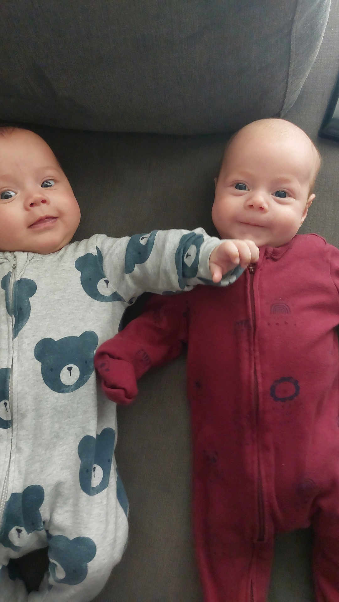 Ethan And Josh is registered to the contest to win money with this photo: baby, infant, onesie, couch, smile, face, child, cute, playful, expression, indoors, fabric, apparel, sitting, two, friendship, together, hand, comfort, soft