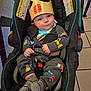 Legend is registered to the contest to win money with this photo: baby, buckle, burger_king, car_seat, cozy, crown, cute, fabric, hands, infant, onesie, portrait, restaurant, seatbelt, smiling, socks, stroller_handle, tiled_floor, truck_pattern, warning_label
