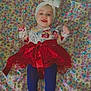 baby, child, tutu, red_skirt, headband, bow, floral_pattern, blanket, colorful, face_filter, heart_shapes, blue_tights, smiling, lying_down, indoors, cute, happy, infant, patterned_clothing, portrait