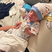 Asher is registered to the contest to win money with this photo: newborn, baby, sleeping, hat, clothing, pillow, cartoon_character, blanket, hand, person, bedroom, bag, towel, floor, water_bottle, fabric, indoor, rest, cute, cozy