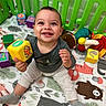 Gabriel is registered to the contest to win money with this photo: baby, child, smiling, happy, portrait, sitting, toy_block, playpen, play_mat, plush_toy, colorful, indoor, nursery, infant, clothing, long_sleeves, socks, facial_expression, looking_at_camera, playtime