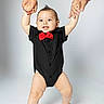 baby, child, infant, smiling, portrait, studio, bow_tie, black_outfit, red, adult_hands, being_held, standing, arms_raised, happy, face, indoor, white_background, fashion, family, photography