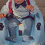 baby, bow_tie, casual_clothing, child, curious, cute, face, footwear, hands, indoor, jeans, person, portrait, ride_on_toy, seatbelt, shirt, smiling, suspenders, toddler, toy_car